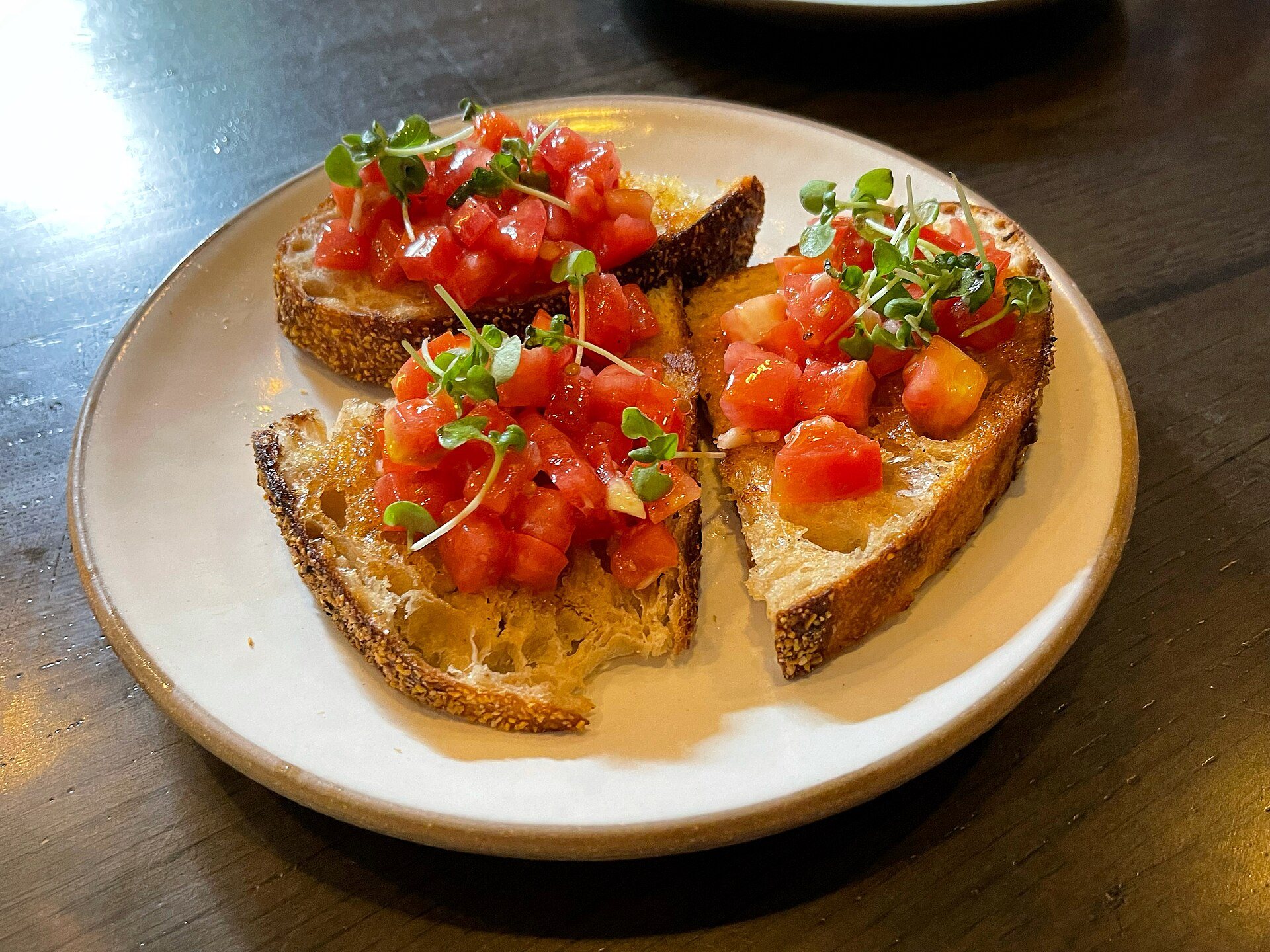 Tomato bruschetta topped with microgreens on a plate